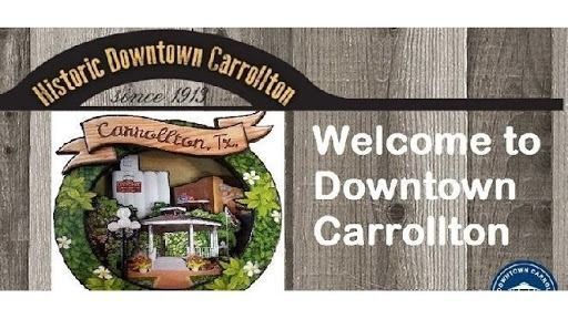 Welcome sign for Historic Downtown Carrollton, Texas, featuring a decorative wreath and text on a wood-grain background.