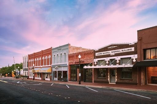 Row of historic brick buildings on a street, with a colorful sunset sky.
