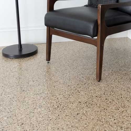 Chair on speckled beige floor with a black lamp base in the corner.