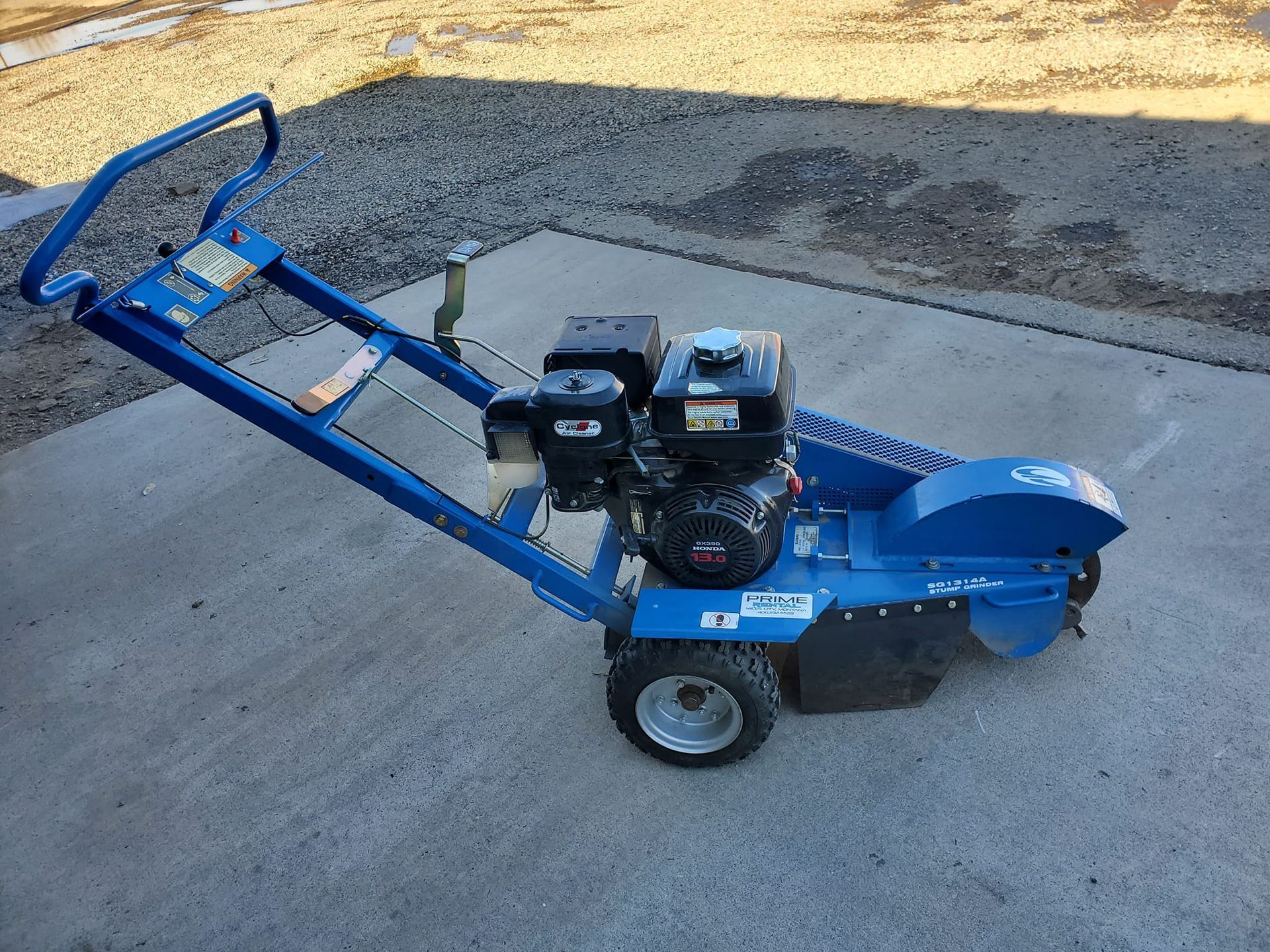 A blue stump grinder is parked on the side of the road.