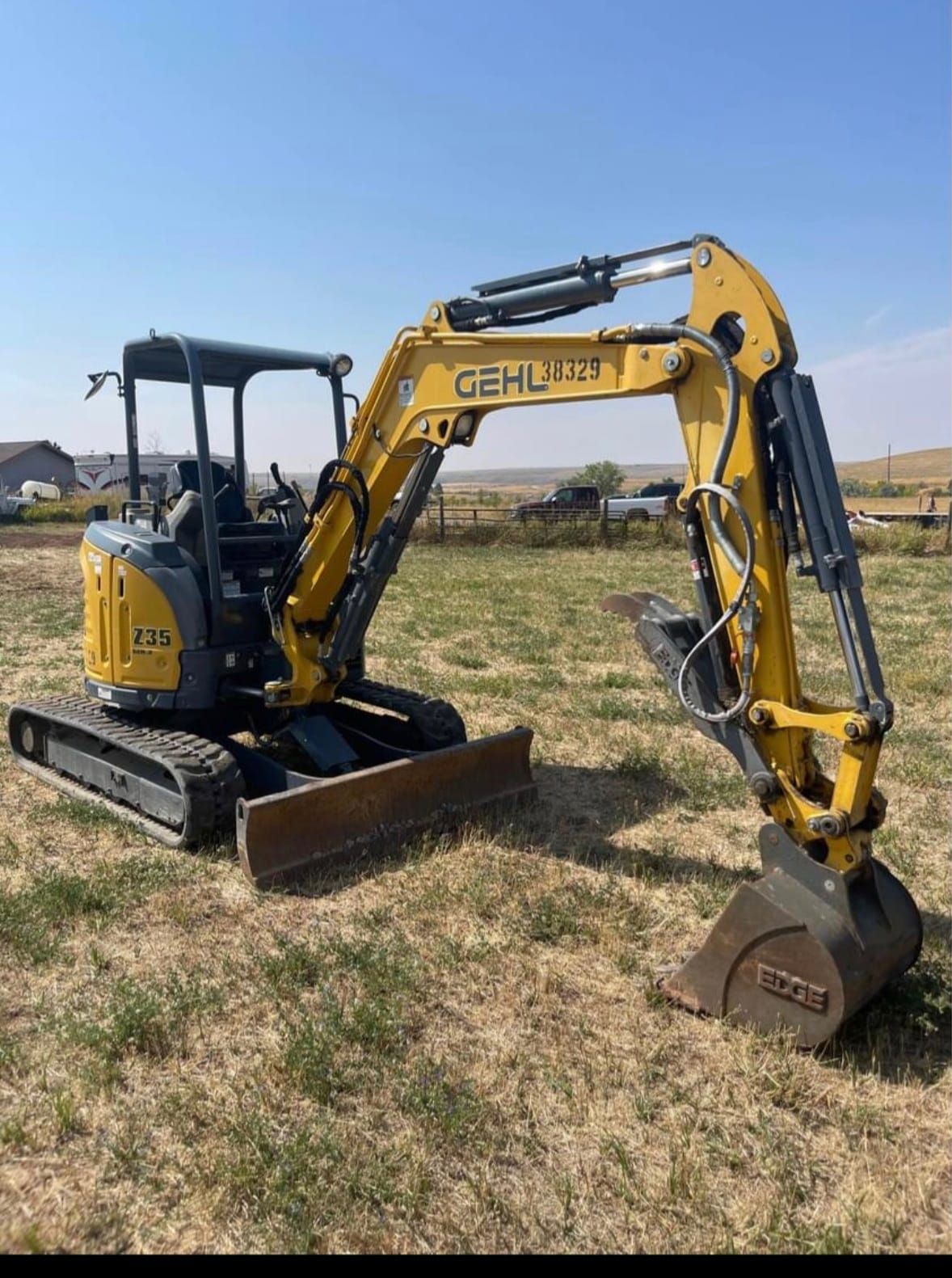 A small yellow excavator is parked in a field.