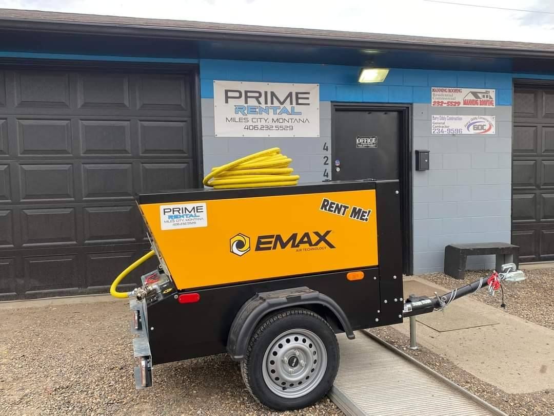 A yellow and black trailer is parked in front of a garage door.
