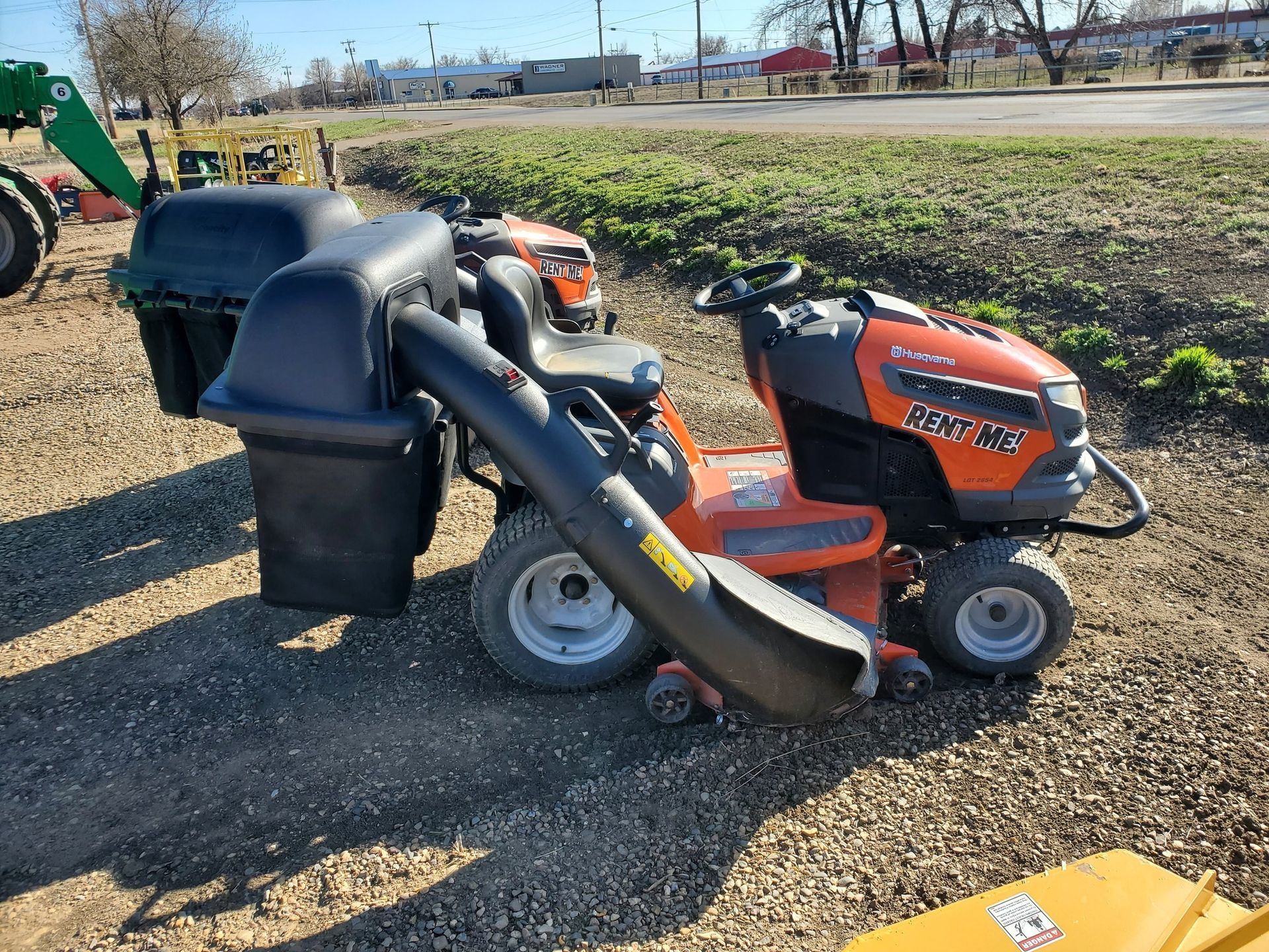 A lawn mower with a vacuum attached to it is parked in a field.