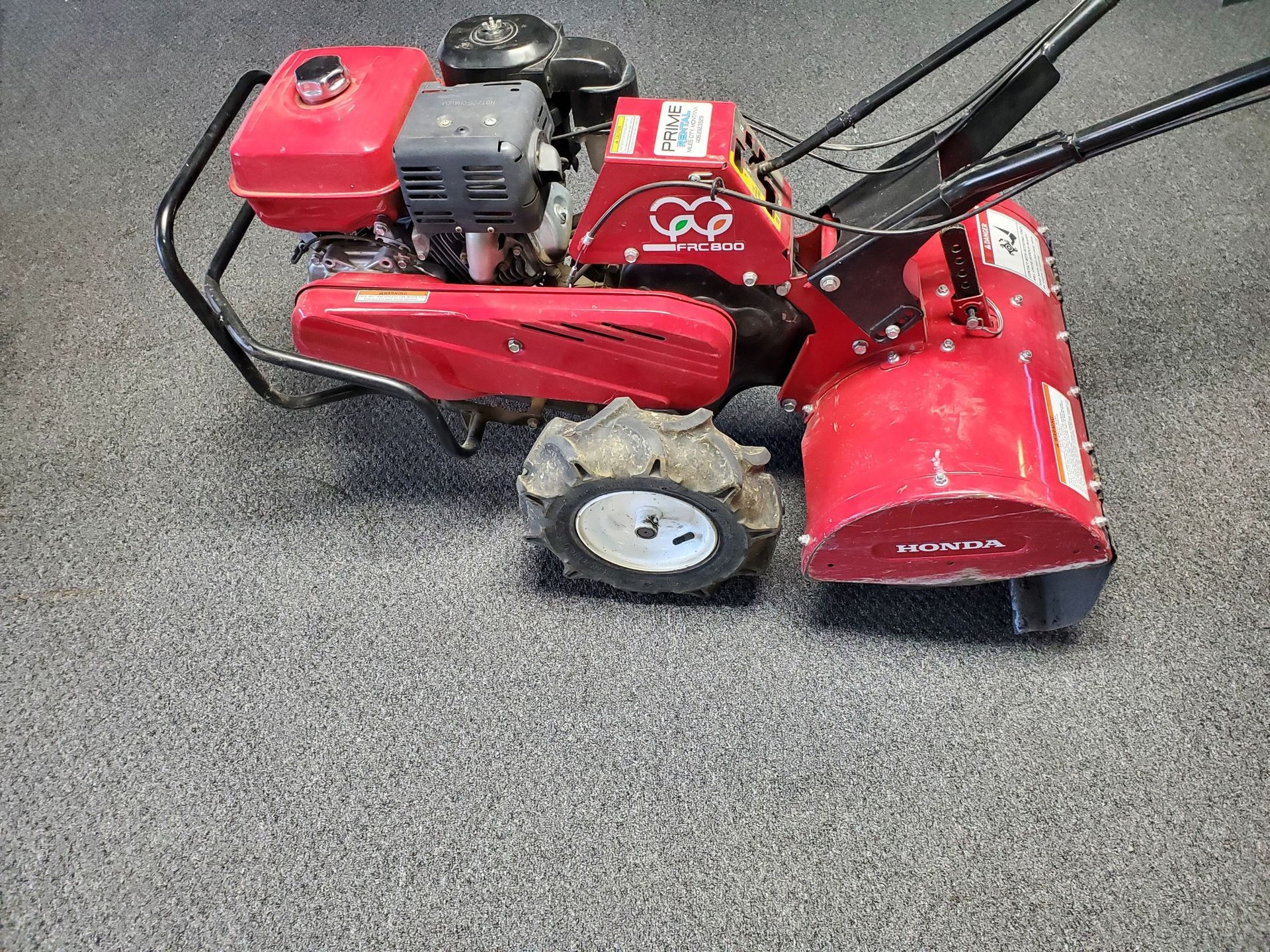 A red lawn mower is sitting on a carpeted floor.