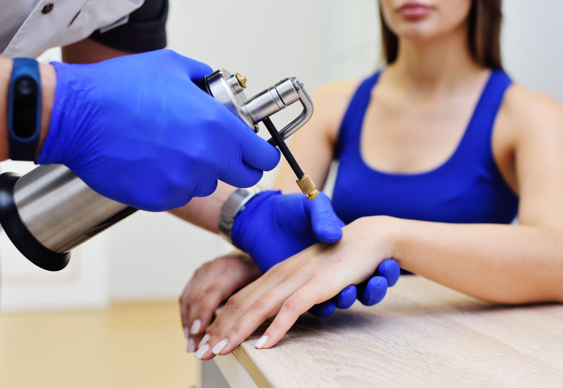 dermatologist uses cryotherapy device on female patient's hand