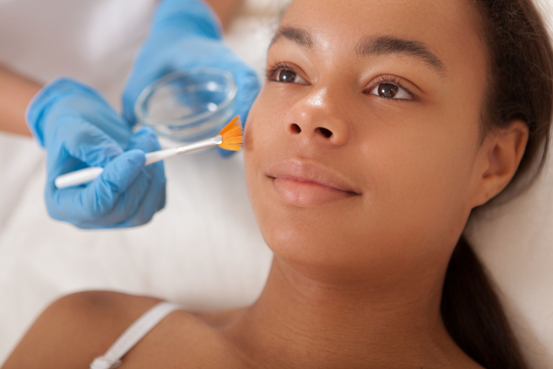 young black woman receives a chemical peel facial treatment