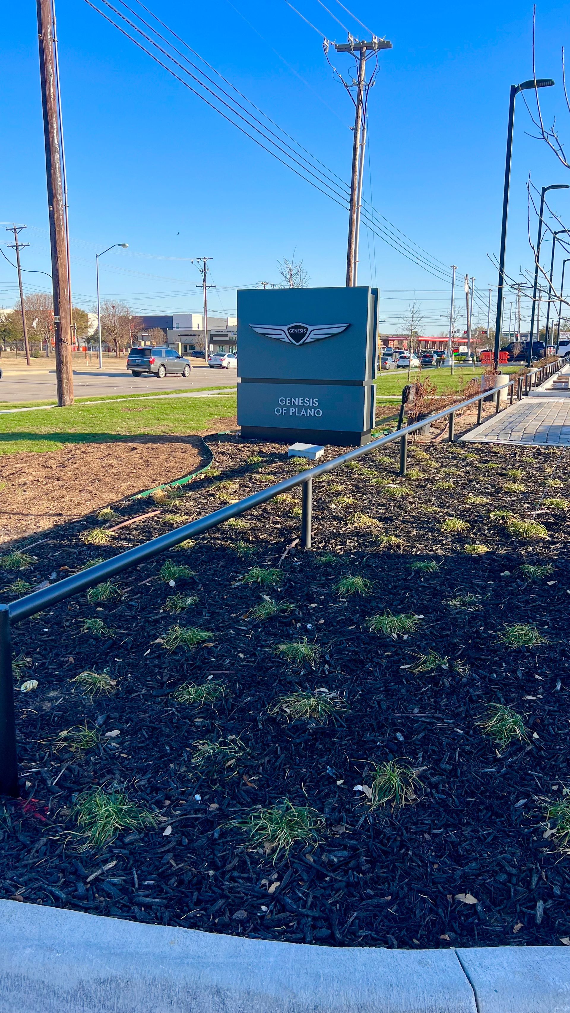 Gray electrical box with logo on stand, in front of a blue sky and highway.
