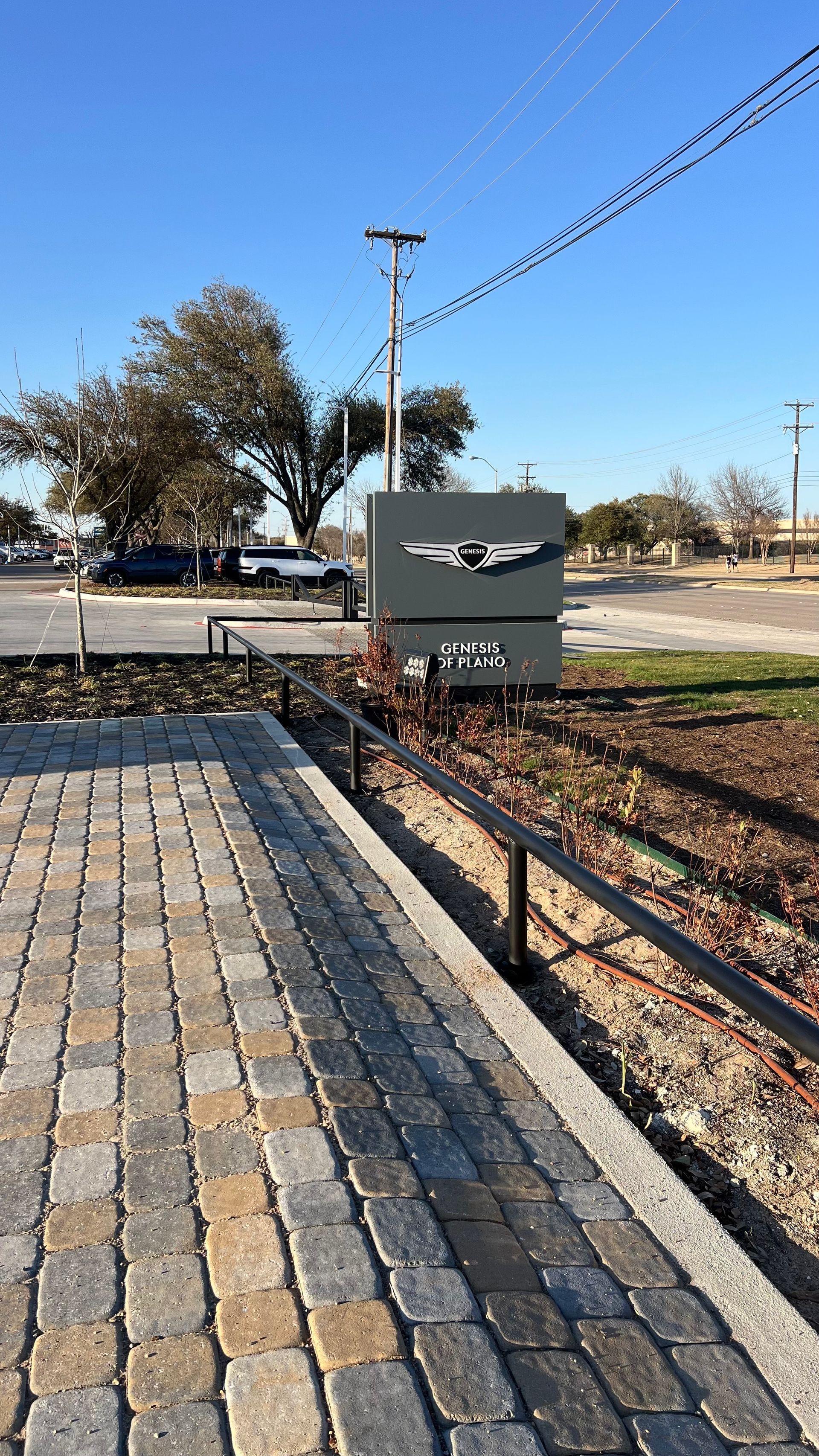 Sign with a bird graphic, on a paved walkway, with a clear sky and sparse vegetation.
