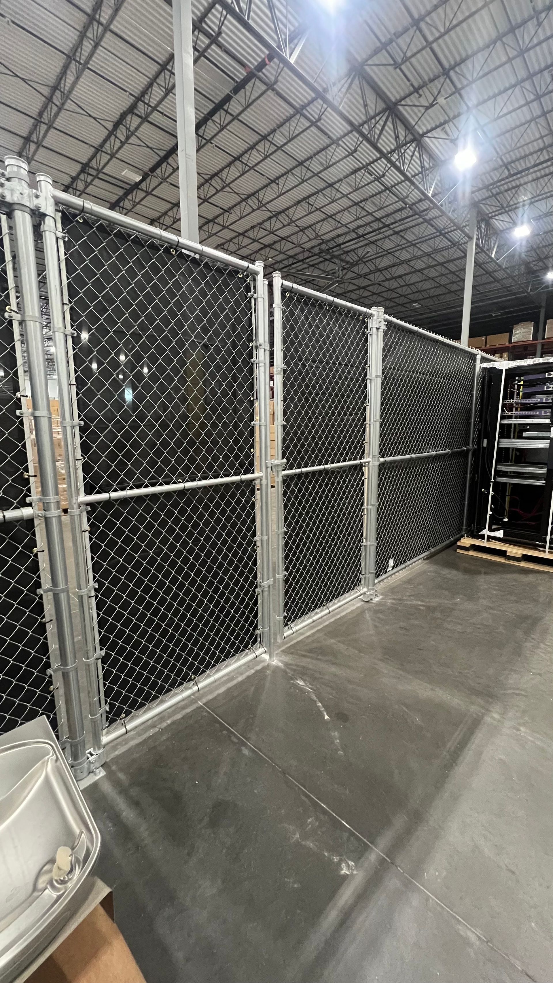 Chain link fence with black privacy slats inside a warehouse.