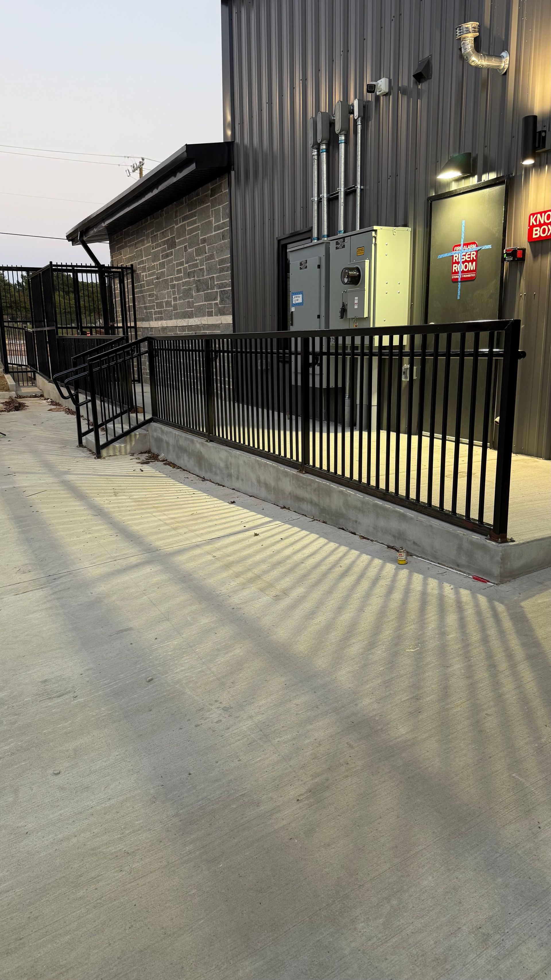 Exterior view of a building with a black metal ramp and railing.