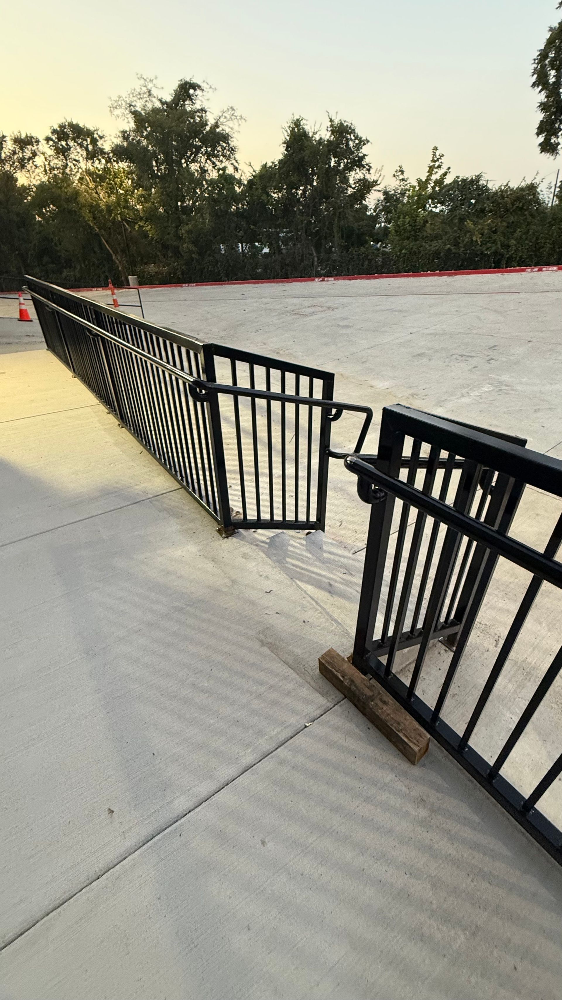A black metal fence is broken on a concrete surface. The fence is angled.