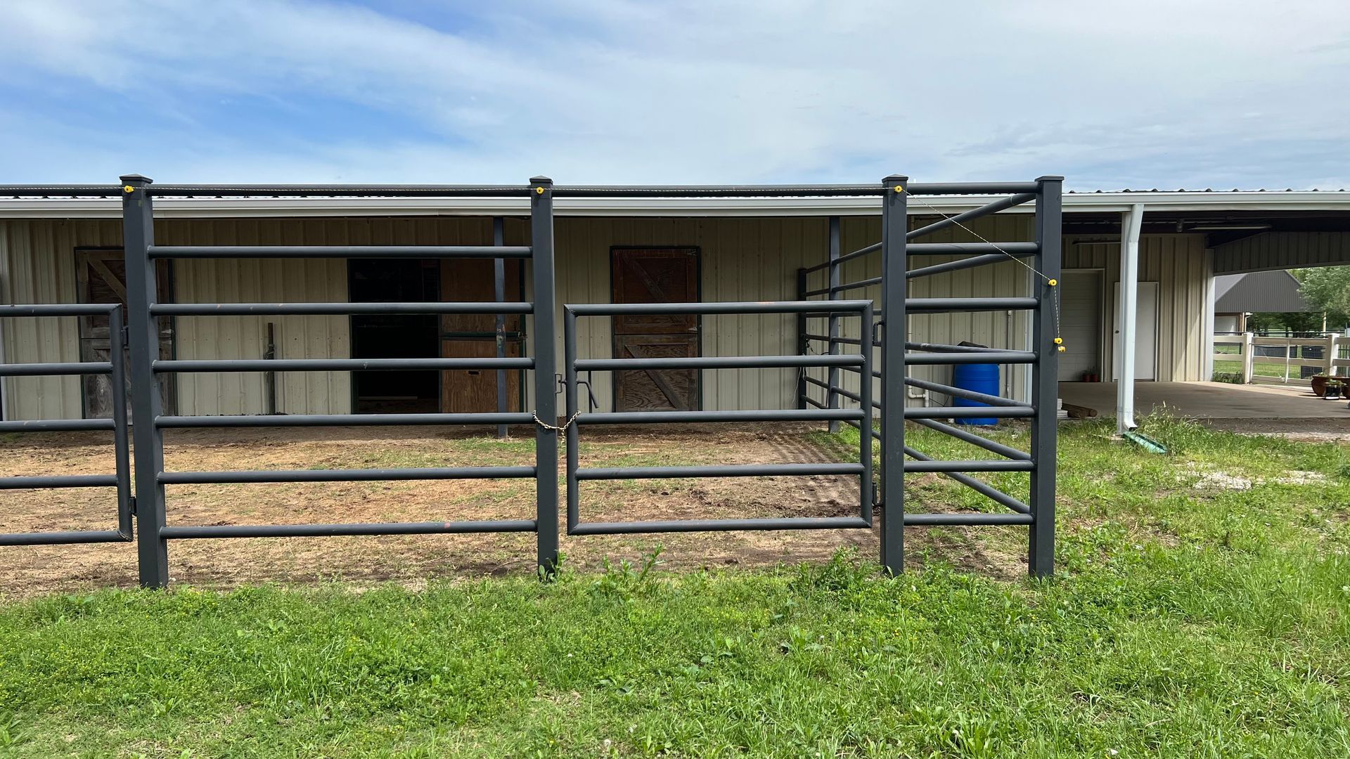 A horse stable with a black fence in front of it.