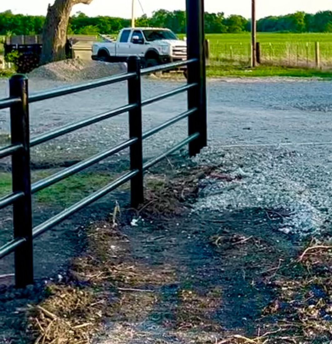 A black fence with a white truck parked behind it.