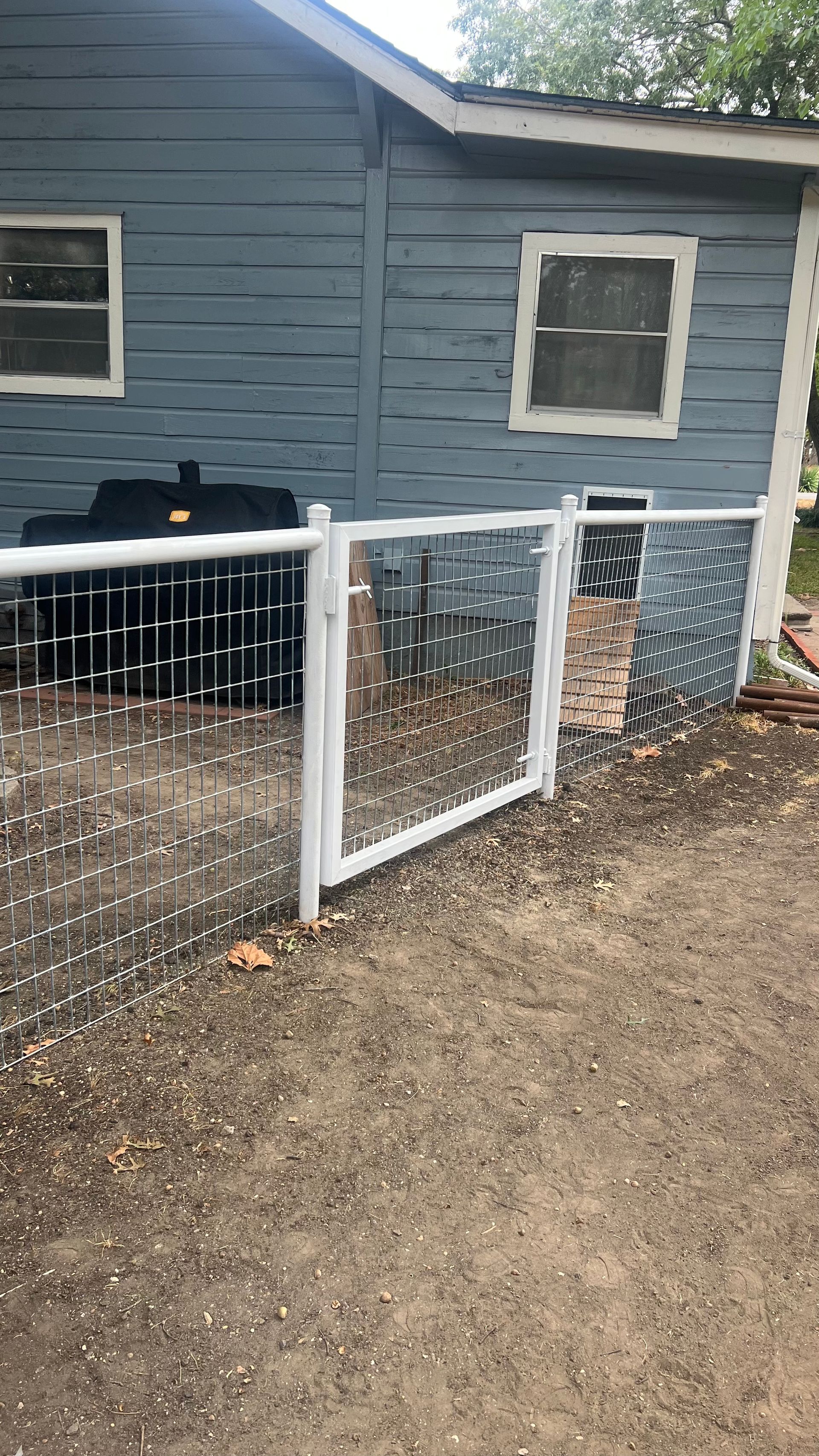 A white fence is sitting in front of a blue house.