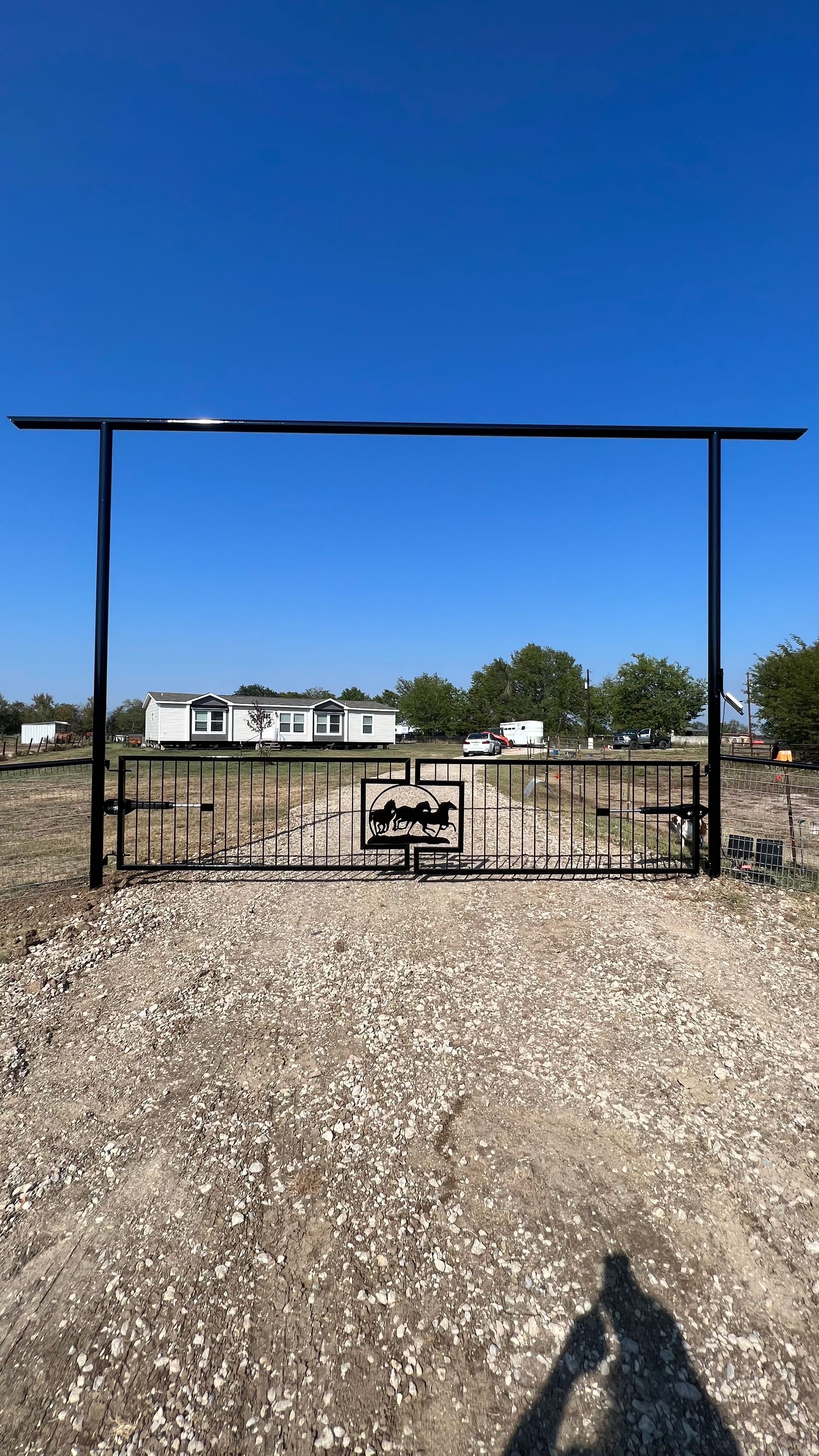 A metal gate is sitting in the middle of a gravel field.