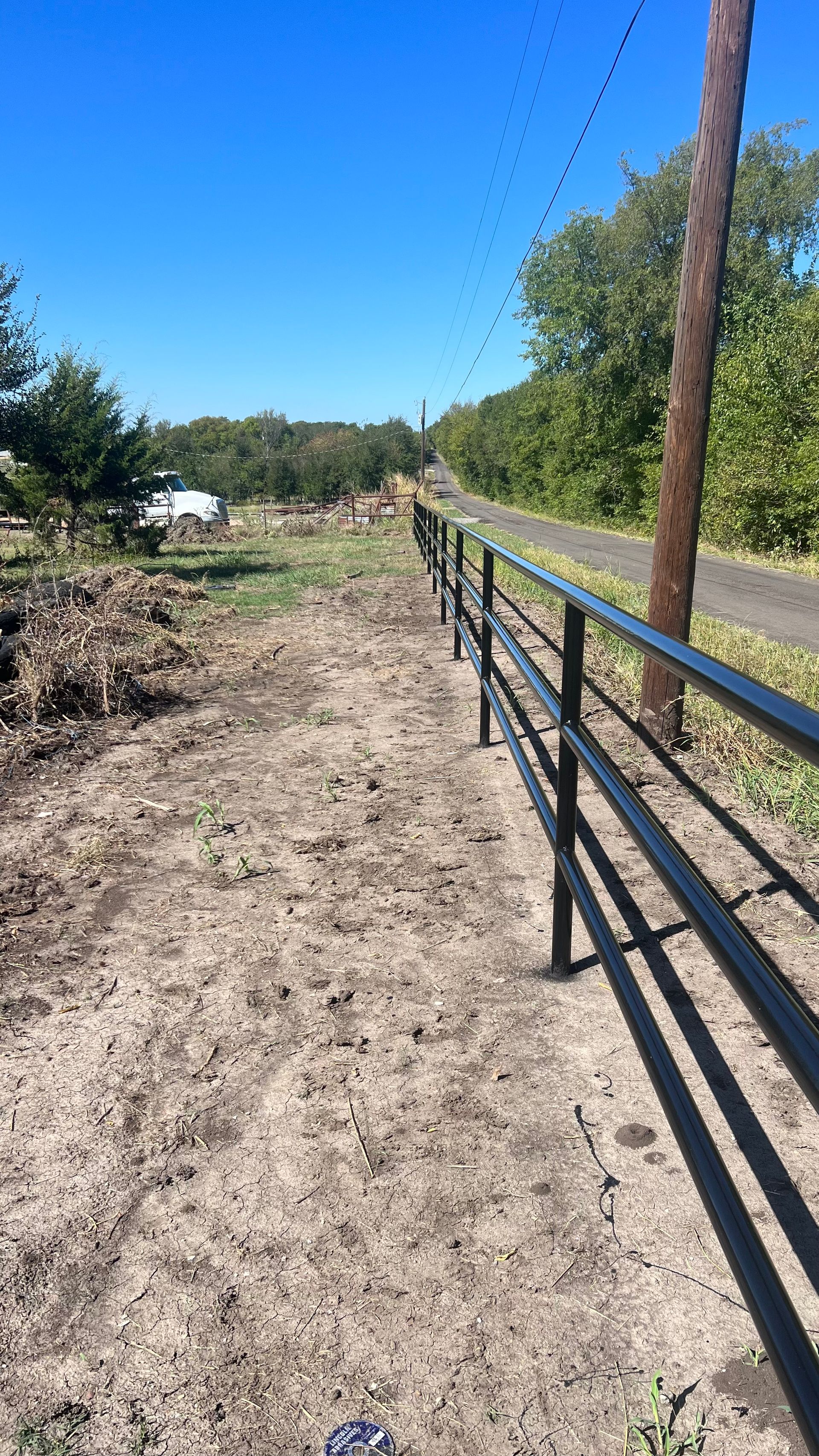 A black metal fence along the side of a dirt road.