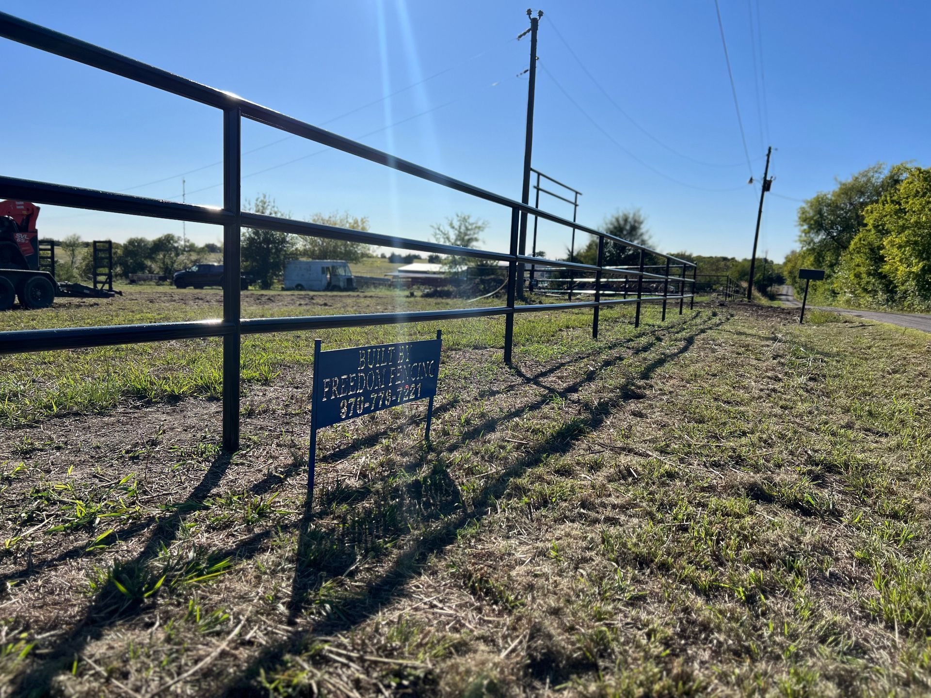 A fence surrounds a grassy field with a sign that says ' fenced in ' on it