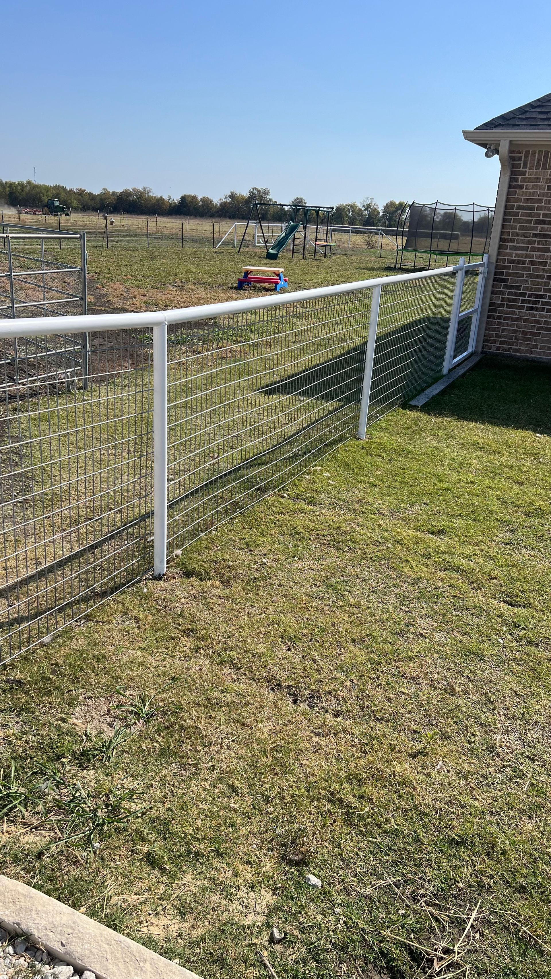 A white fence surrounds a lush green field.