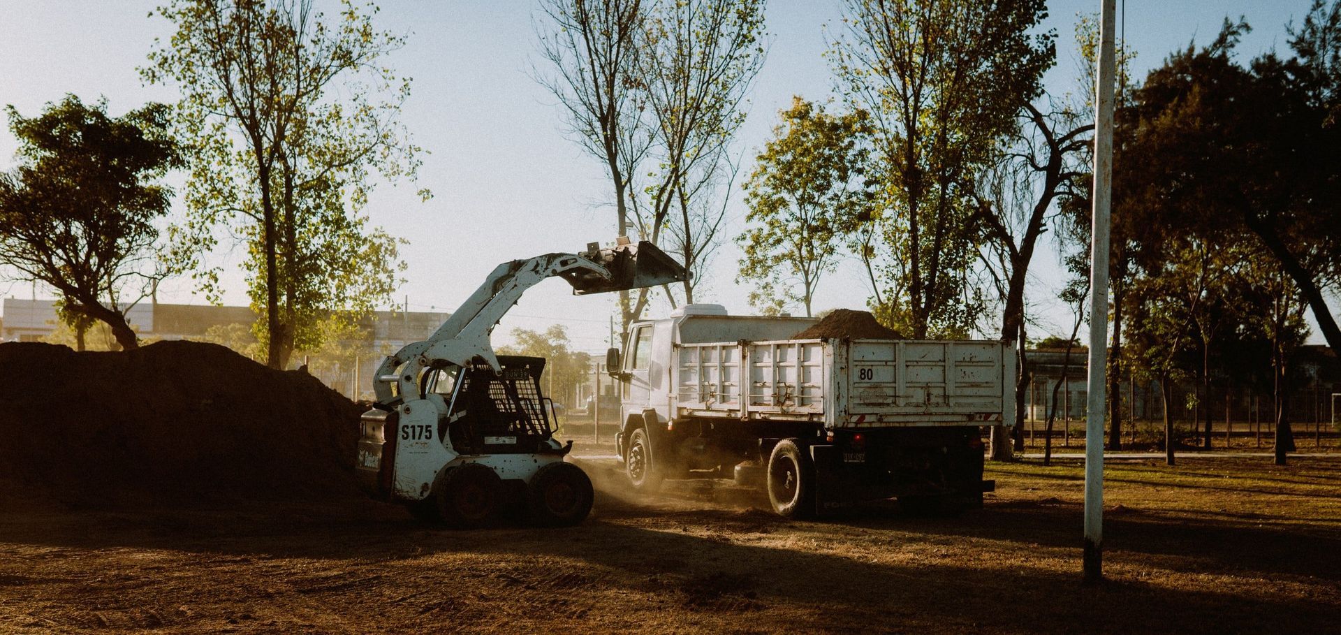A bulldozer is loading dirt into a dump truck