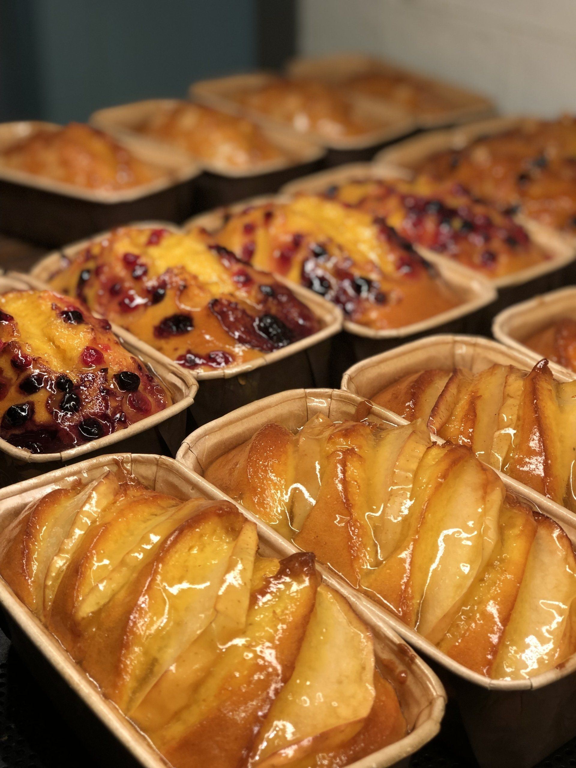 File di mini plumcake dorati ricoperti di frutta e glassati.