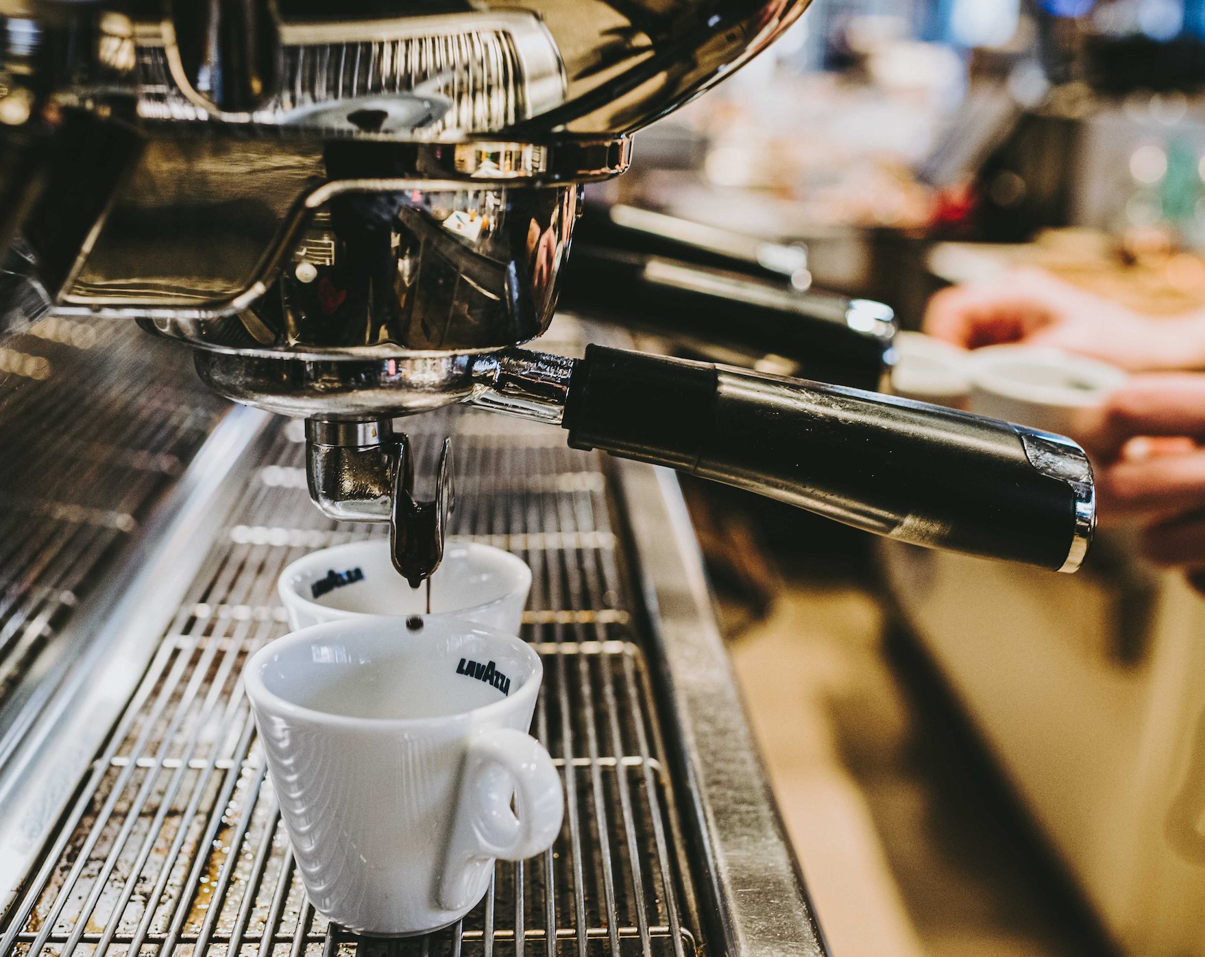 Macchina per caffè espresso che versa il caffè in due tazze bianche su una griglia metallica.