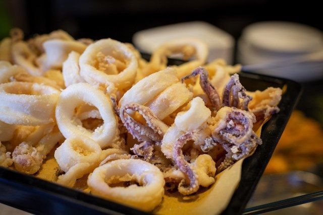 Anelli e tentacoli di calamari fritti in un vassoio nero.