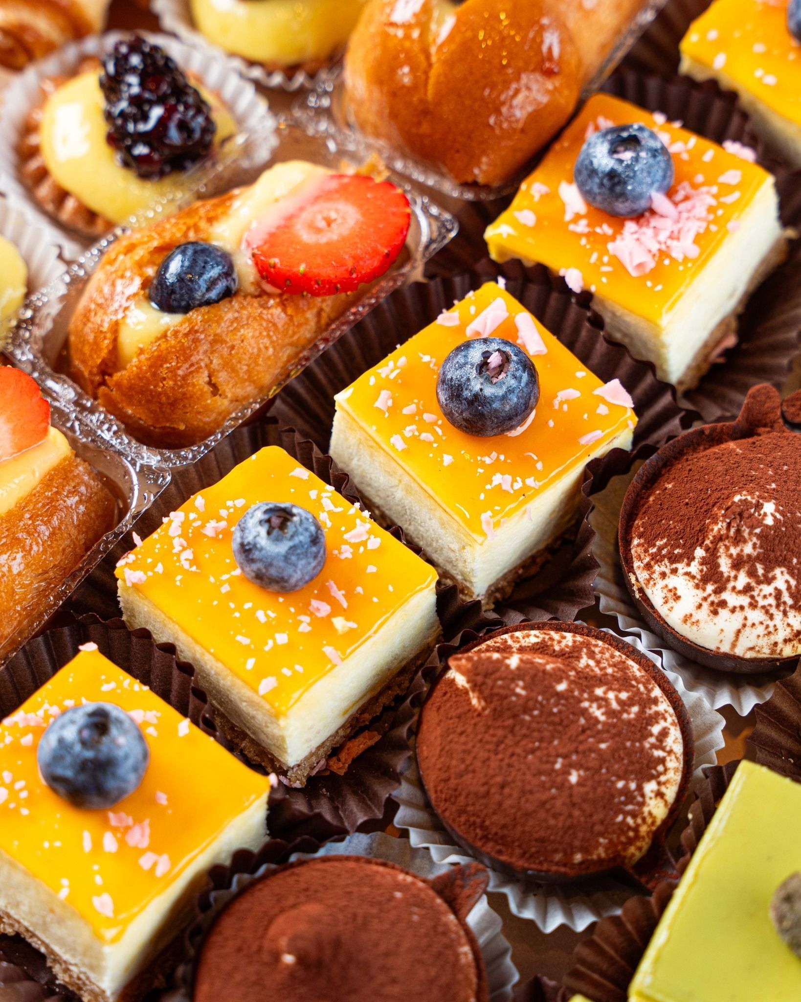 Primo piano di vari mini pasticcini e dessert in singoli bicchieri di carta; alcuni guarniti con frutta.