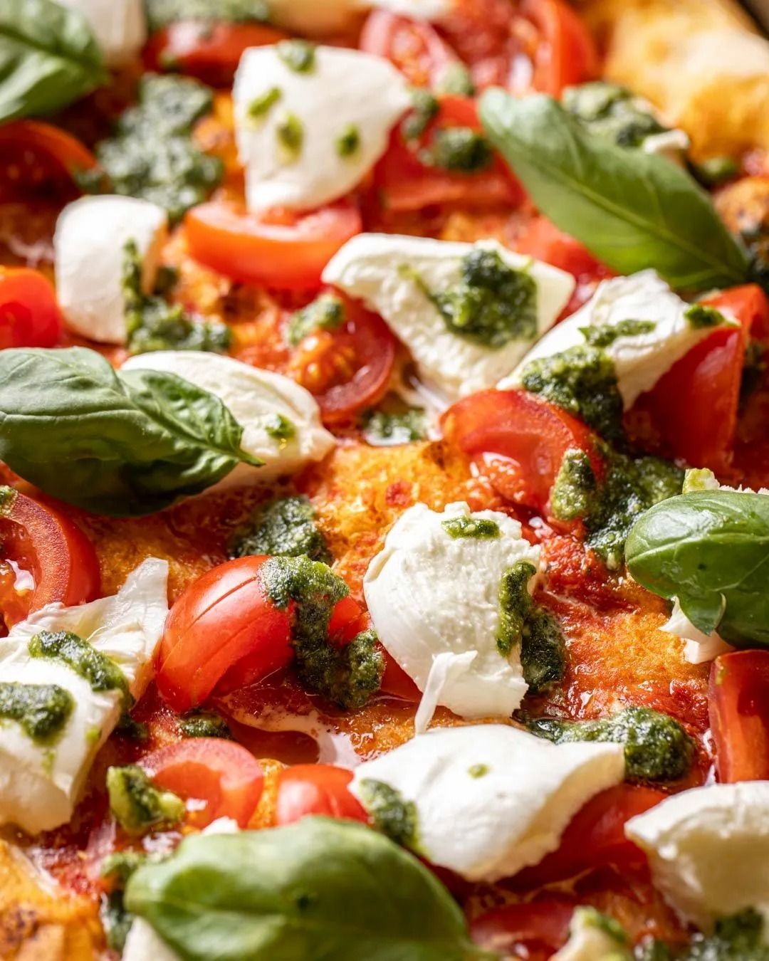 Pizza con mozzarella, pomodori, pesto e basilico.