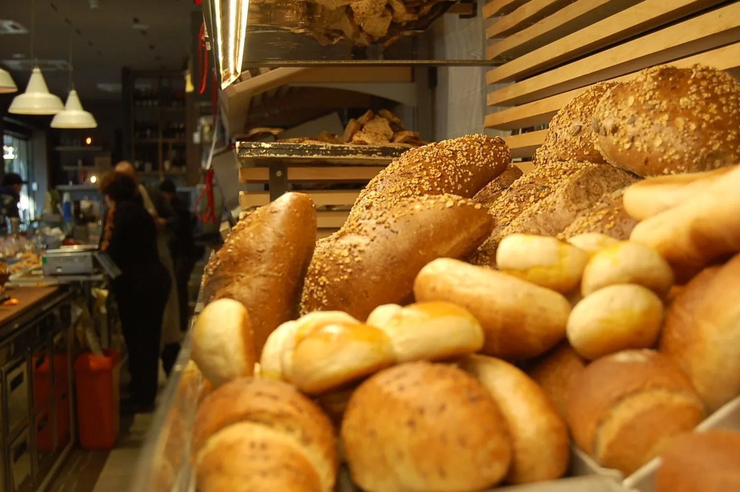 Esposizione di vari tipi di pane, alcuni con semi di sesamo. Sullo sfondo, l'interno del negozio.