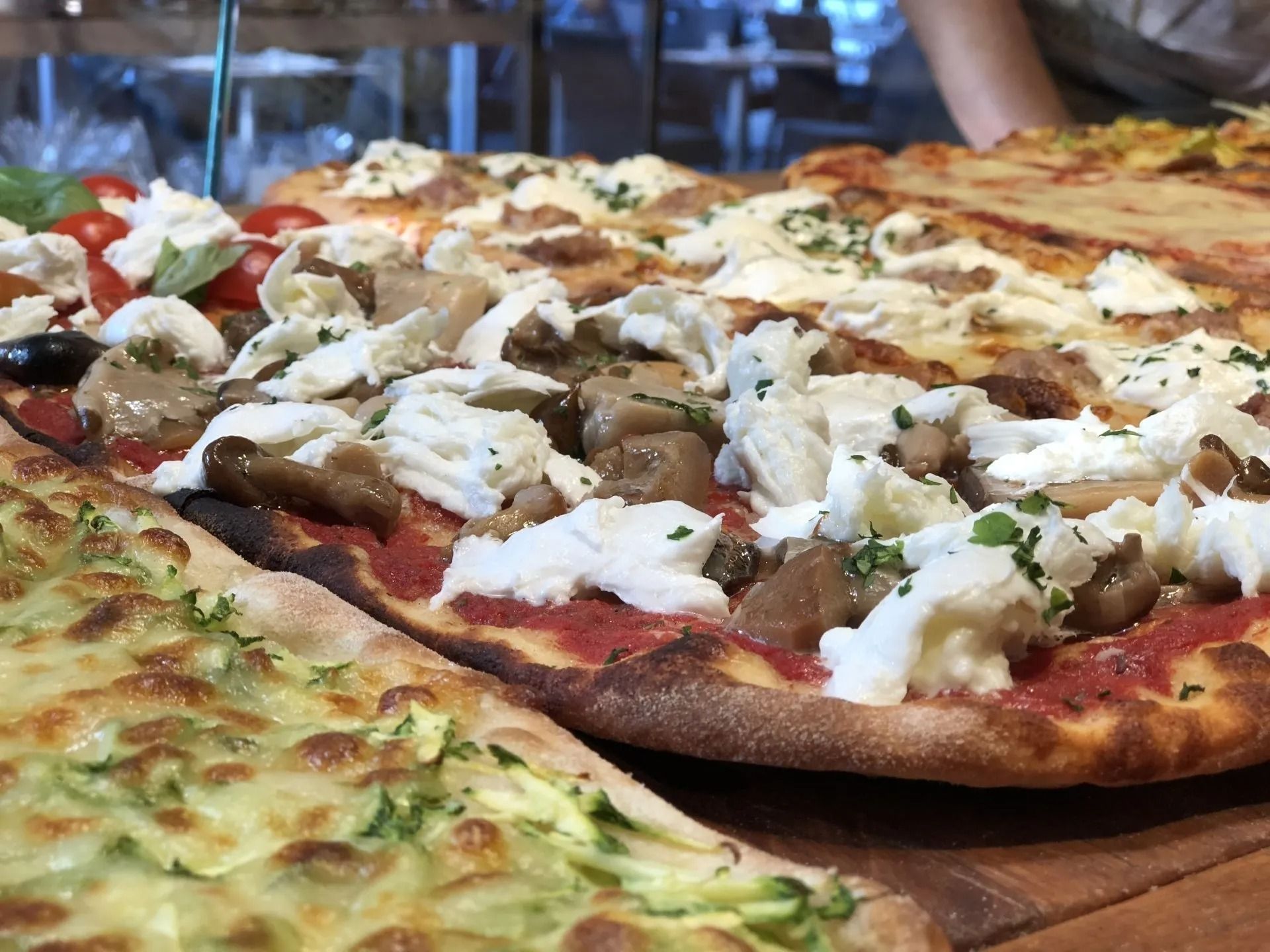 Diverse pizze farcite con verdure e formaggio su un tagliere di legno.