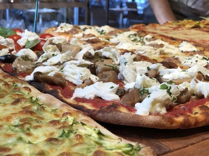 Diverse pizze farcite con verdure e formaggio su un tagliere di legno.