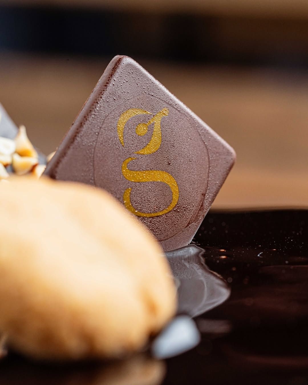 Dessert al cioccolato con un pezzo quadrato di cioccolato ghiacciato contrassegnato da una "S" dorata.