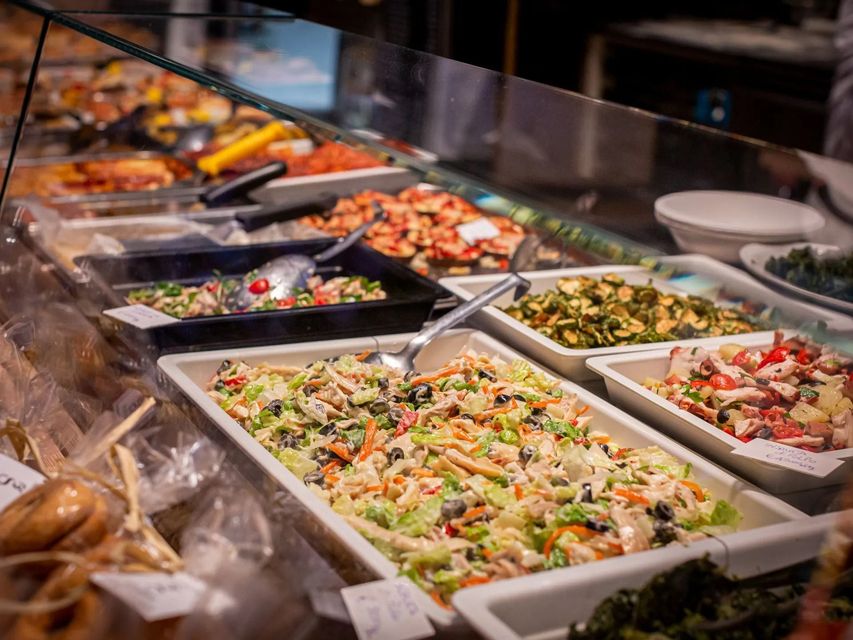 Vetrina buffet con varie insalate e piatti, tra cui frutti di mare, in un ambiente ben illuminato.