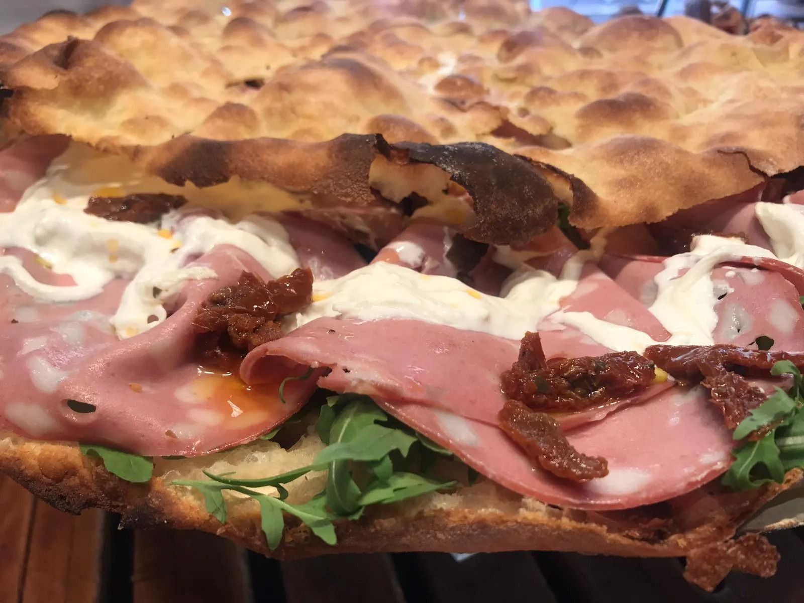 Focaccia con mortadella, rucola, pomodori secchi e salsa.