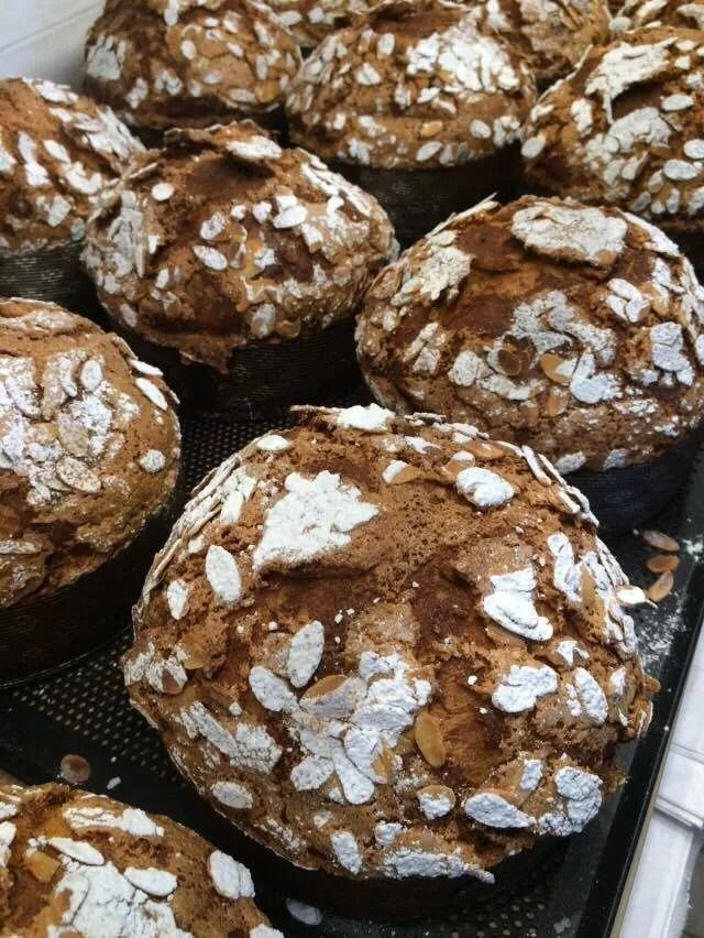 Primo piano di diversi prodotti da forno rotondi e marroni ricoperti di fettine di mandorle.