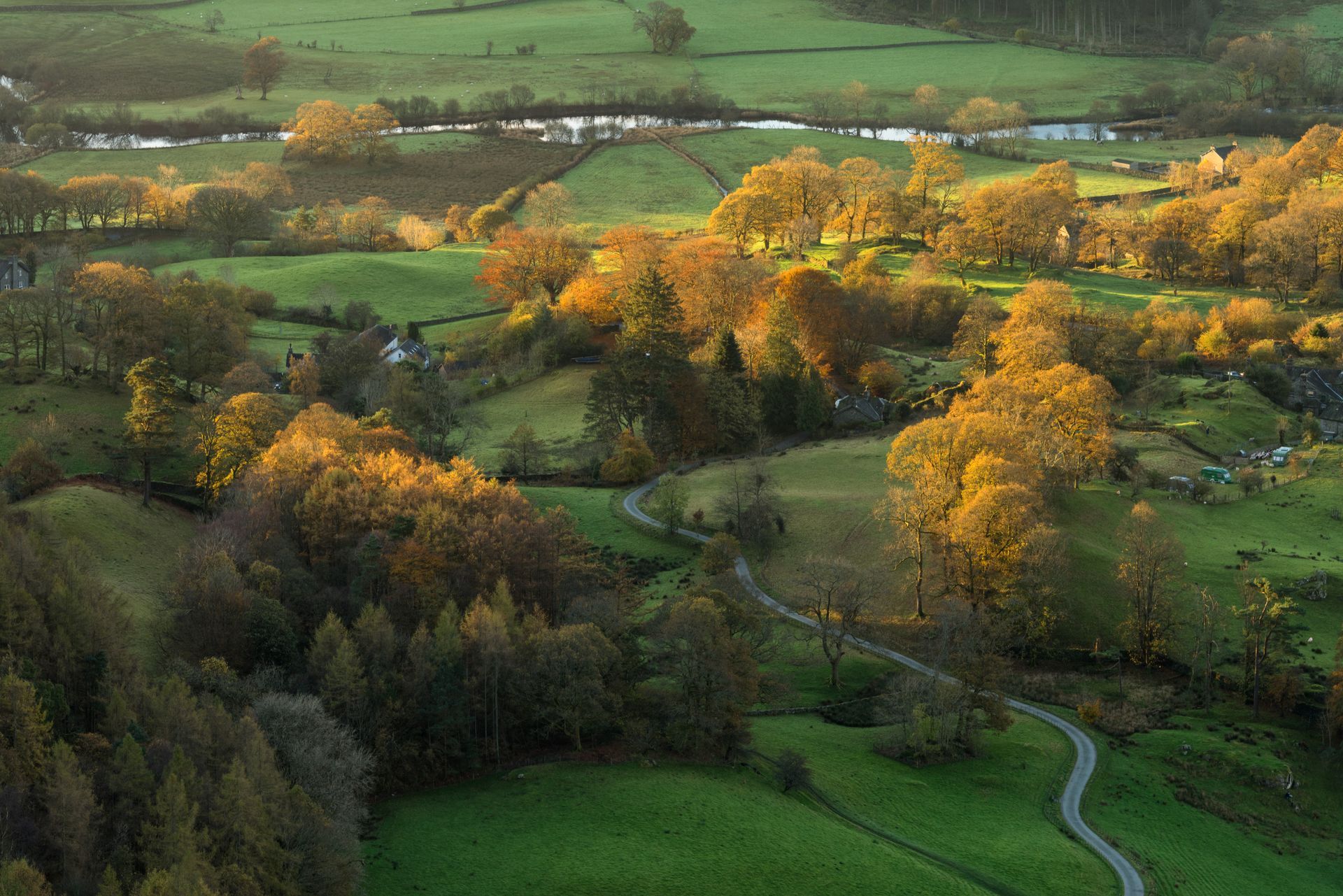 Sprawling countryside hills in sunset. Autumn trees beside a river.