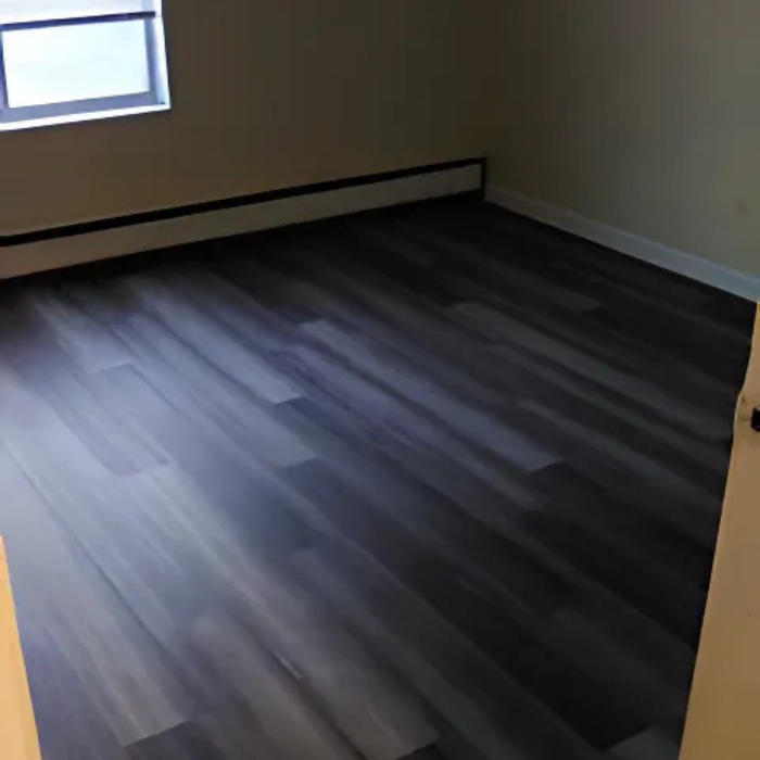A room with a gray wooden floor and a window.