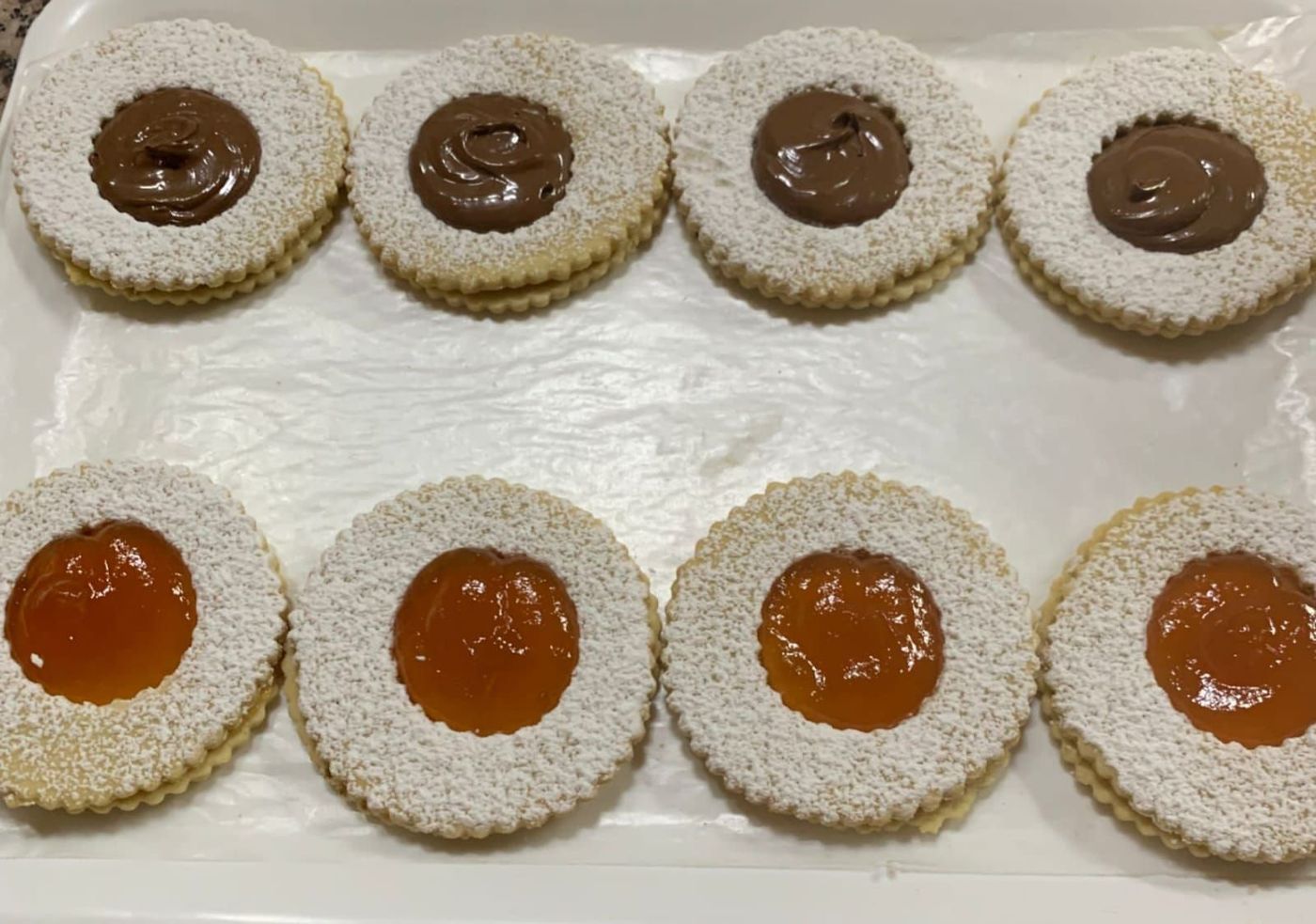 Un vassoio di biscotti con zucchero a velo e marmellata sopra