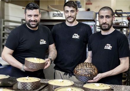 Tre uomini in camicia nera sono in piedi uno accanto all'altro e tengono in mano delle torte.