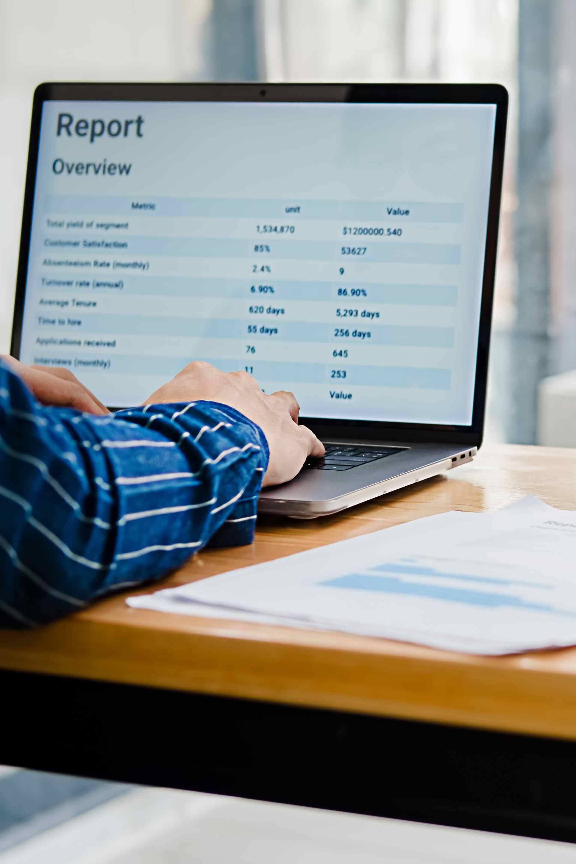 A person is using a laptop computer with a report on the screen.