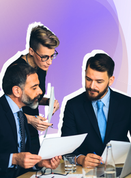 A group of business people are sitting at a table looking at papers.