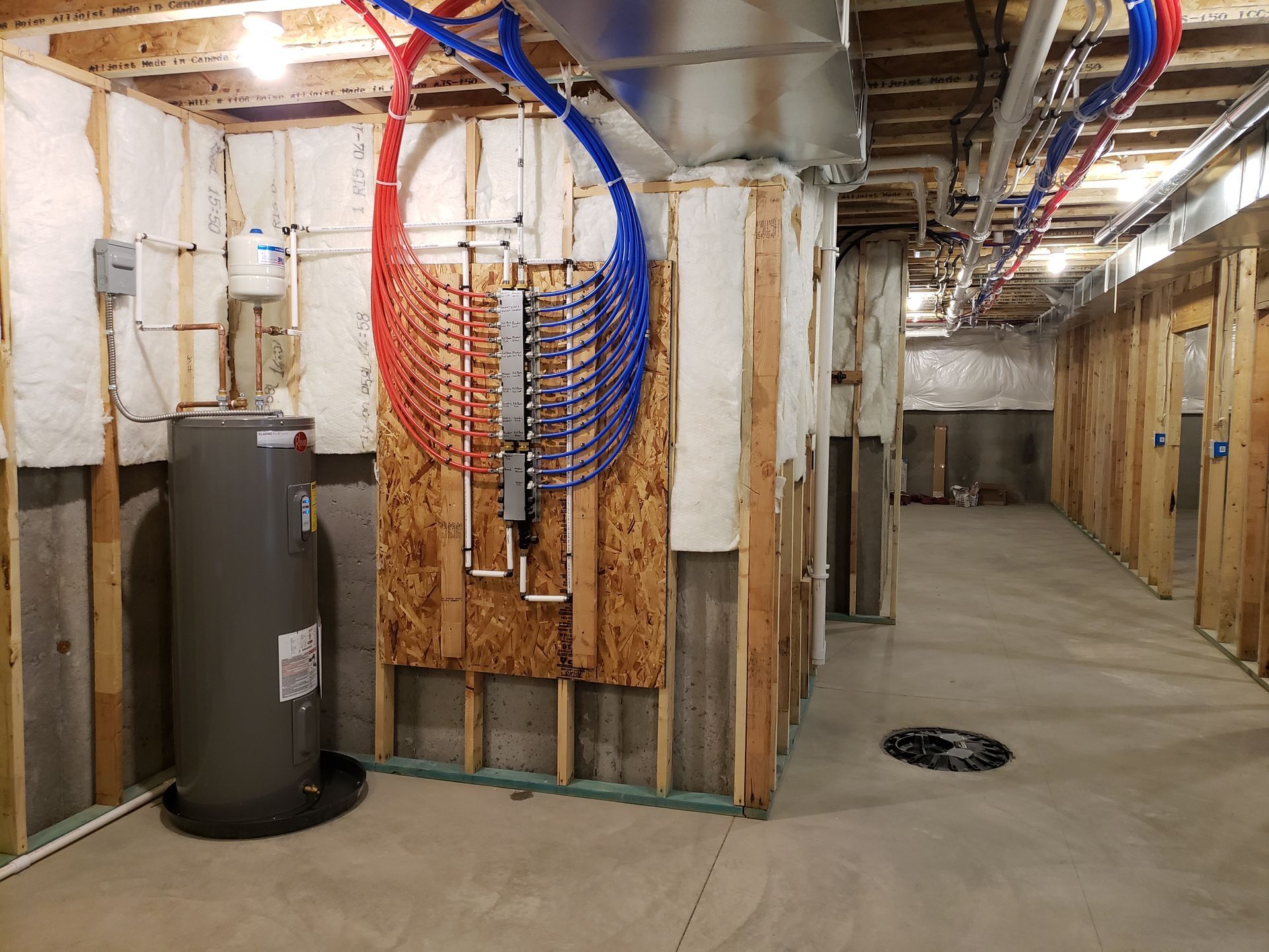 Basement with hot water heater, plumbing, and partially constructed walls.