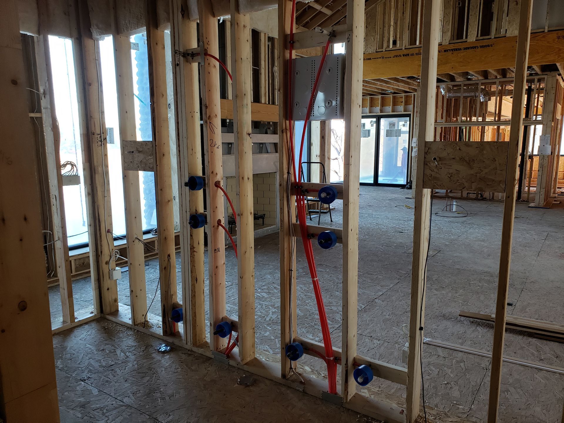 Interior view of a building under construction, showing wooden framing, plumbing, and electrical boxes.