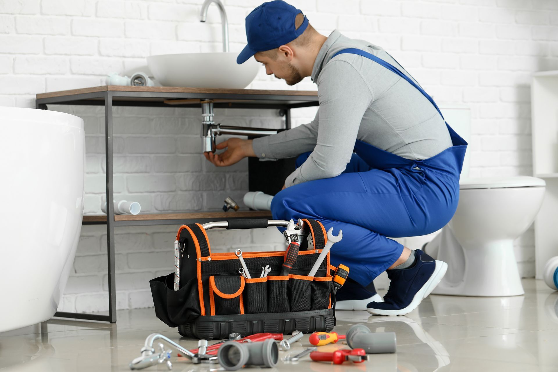 A local plumber is repairing a sink in the bathroom.