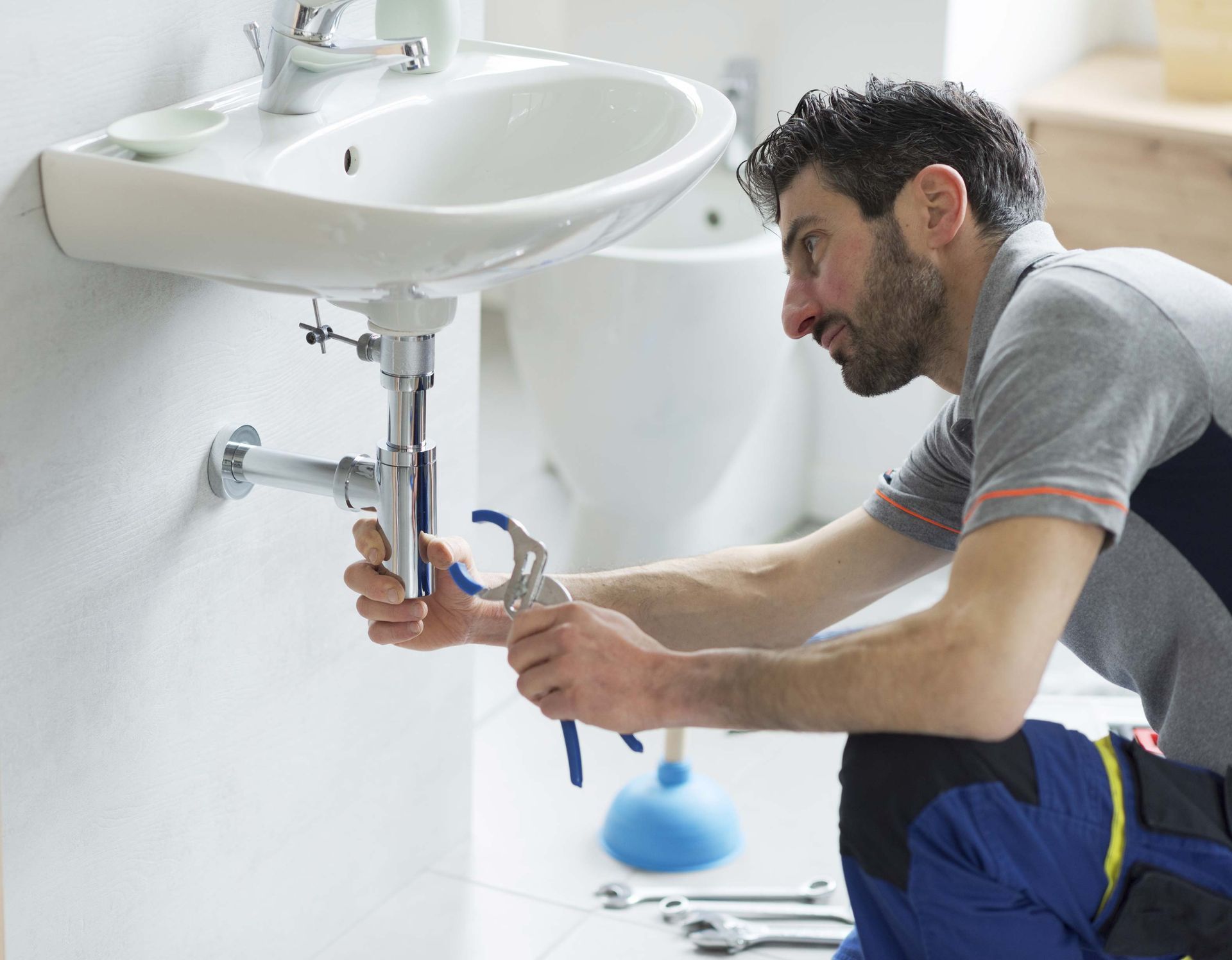 Plumber checking a bathroom sink drain for a clog issue.