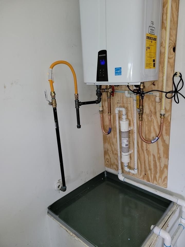 A white water heater is mounted to a wall next to a sink.