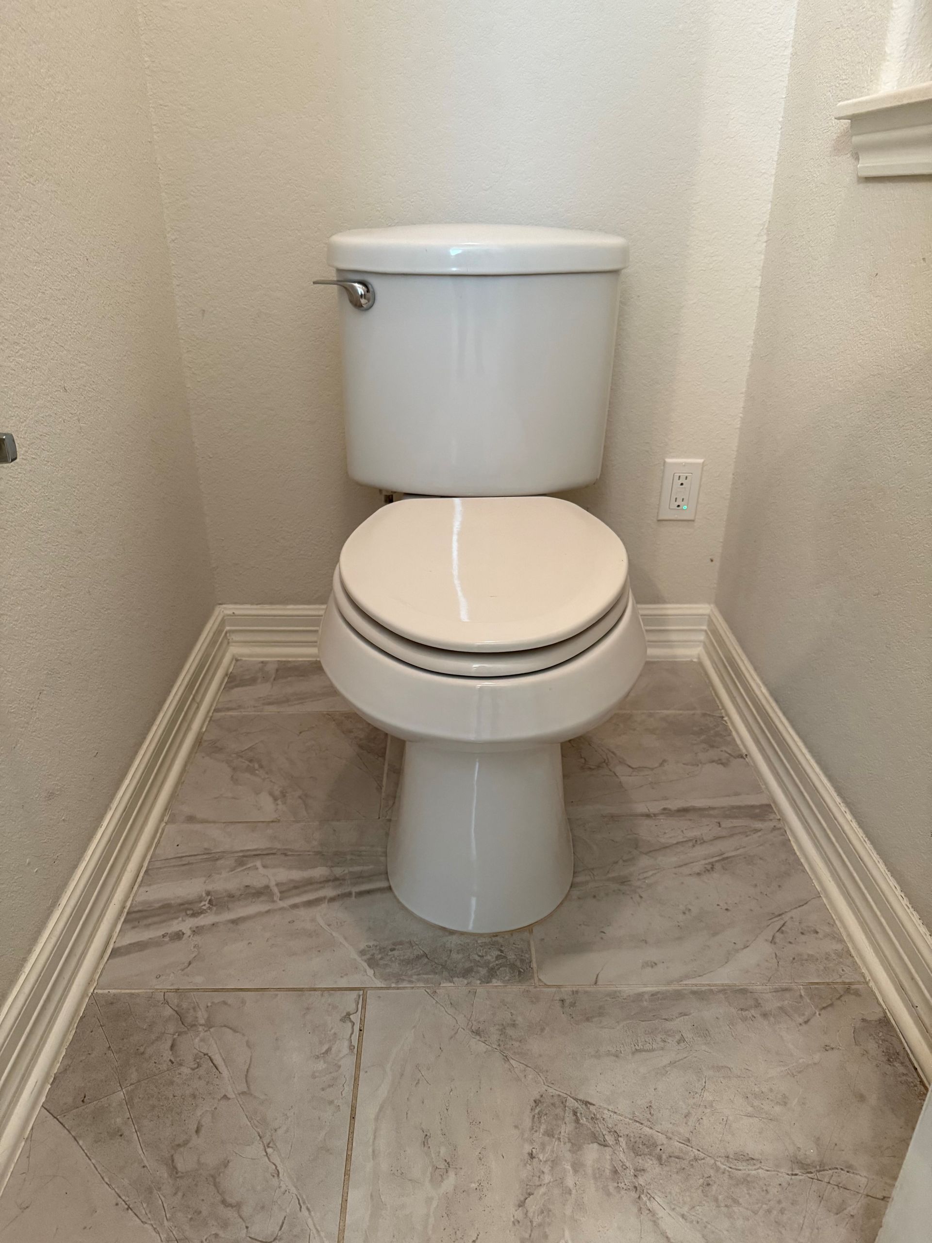 A toilet is sitting on a tiled floor in a bathroom.