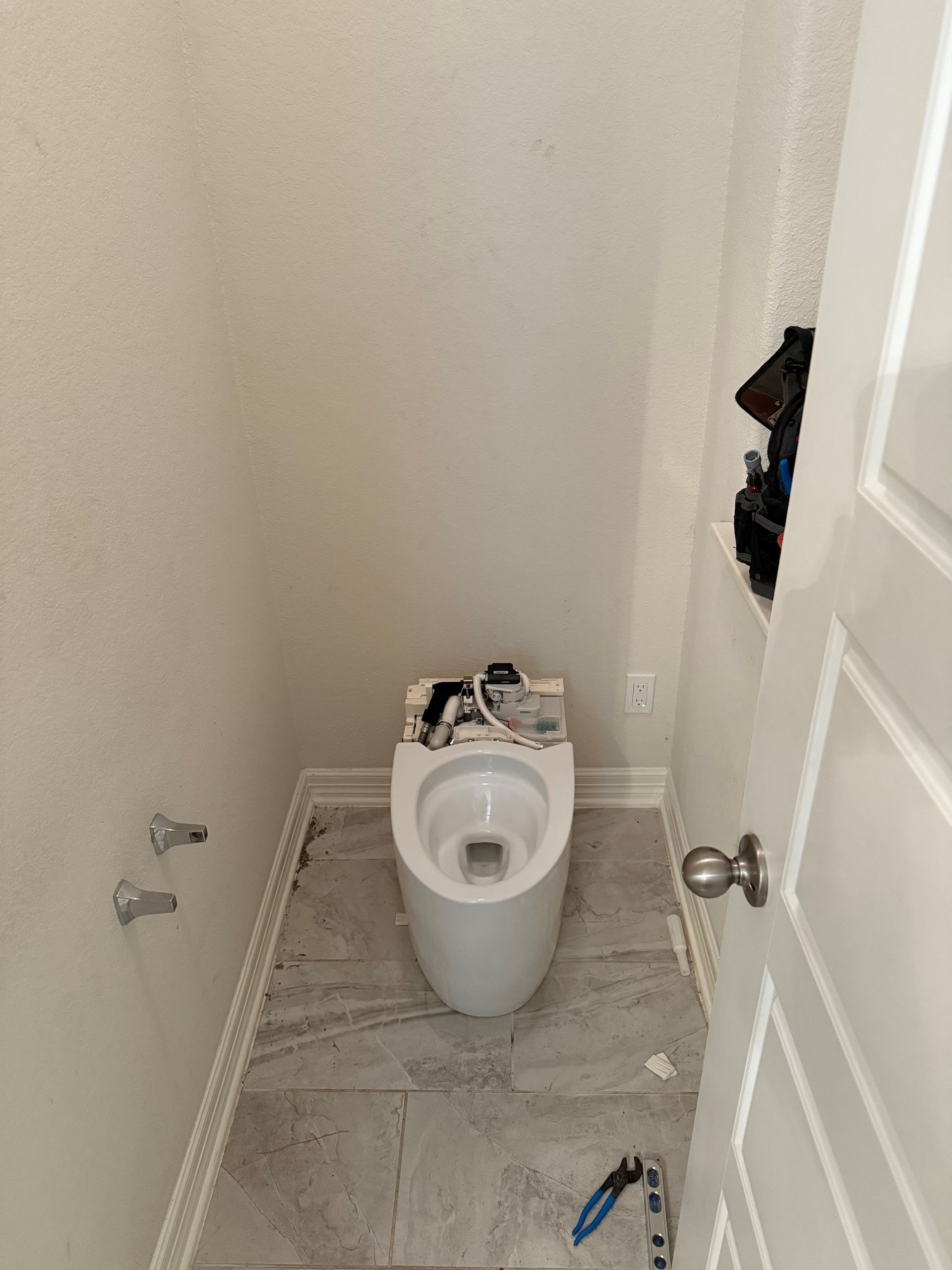 A toilet is sitting in a small bathroom next to a door.