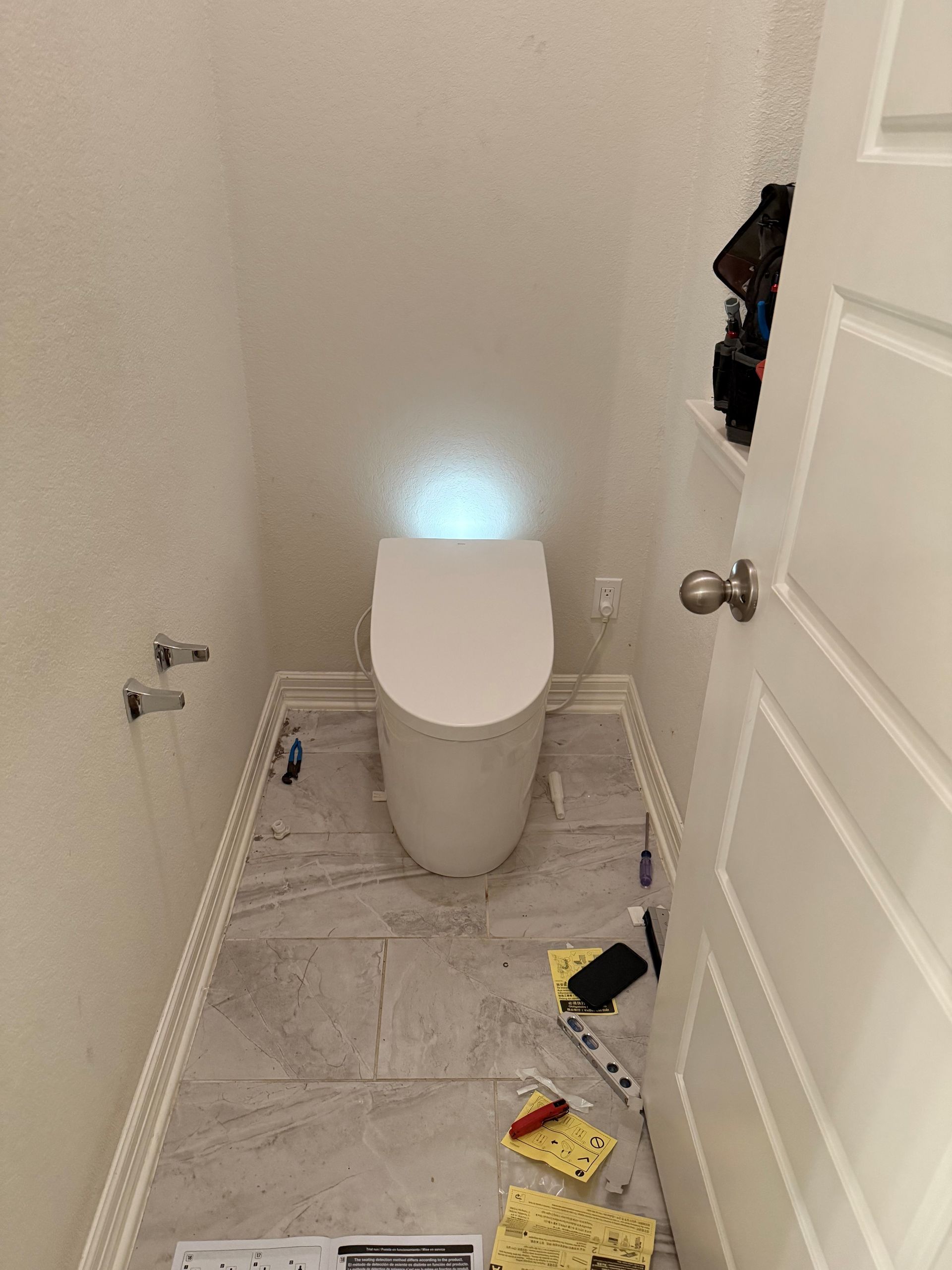 A toilet is sitting in a small bathroom next to a door.