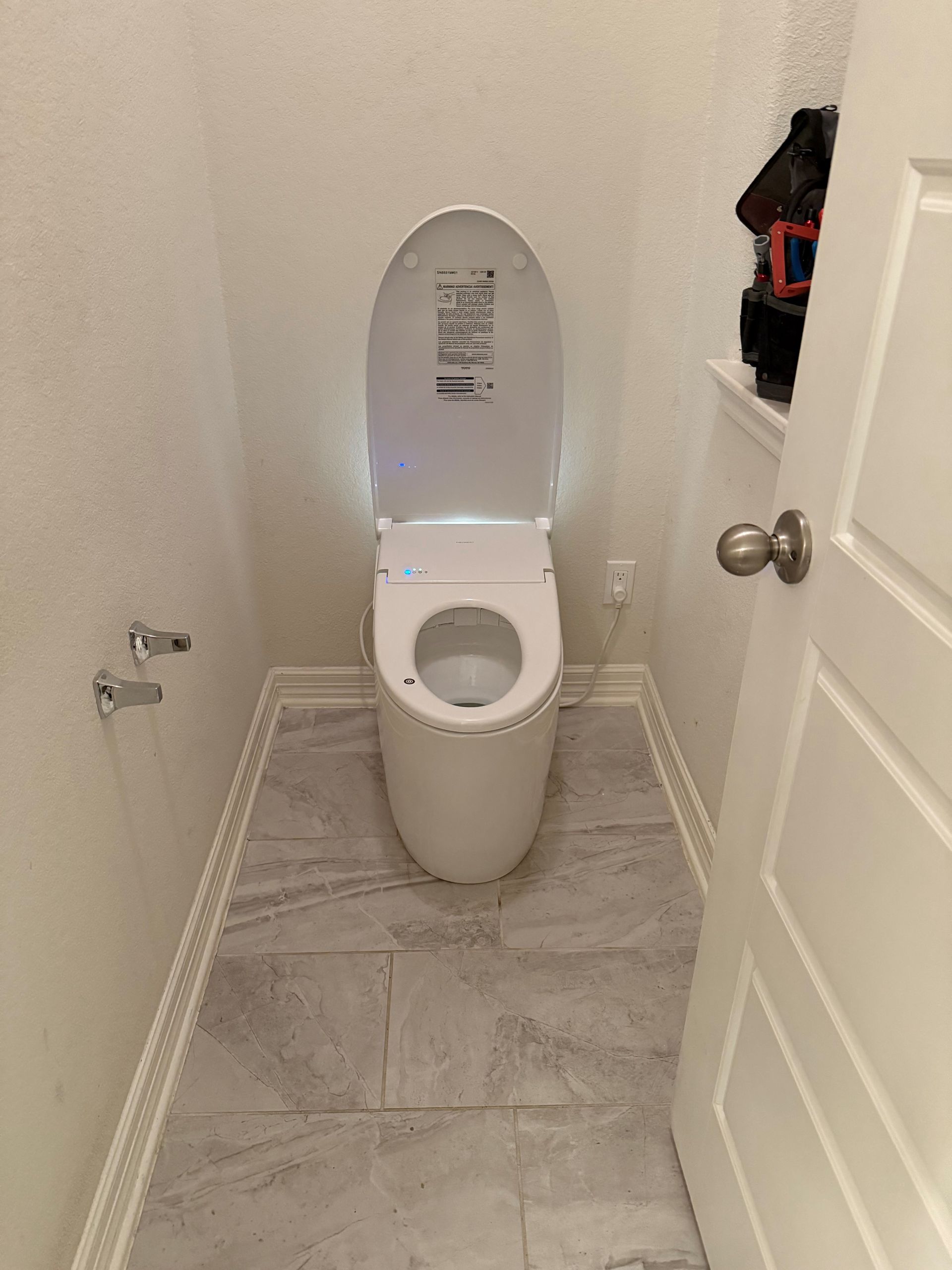A white toilet is sitting in a bathroom next to a door.